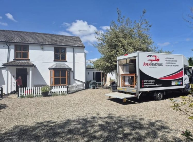 Apex Removals luton van with tail lift down outside a white cottage on a family move